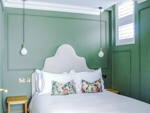 Un dormitorio con una cama, dos lámparas de noche, una mesita de noche y una ventana con persianas.