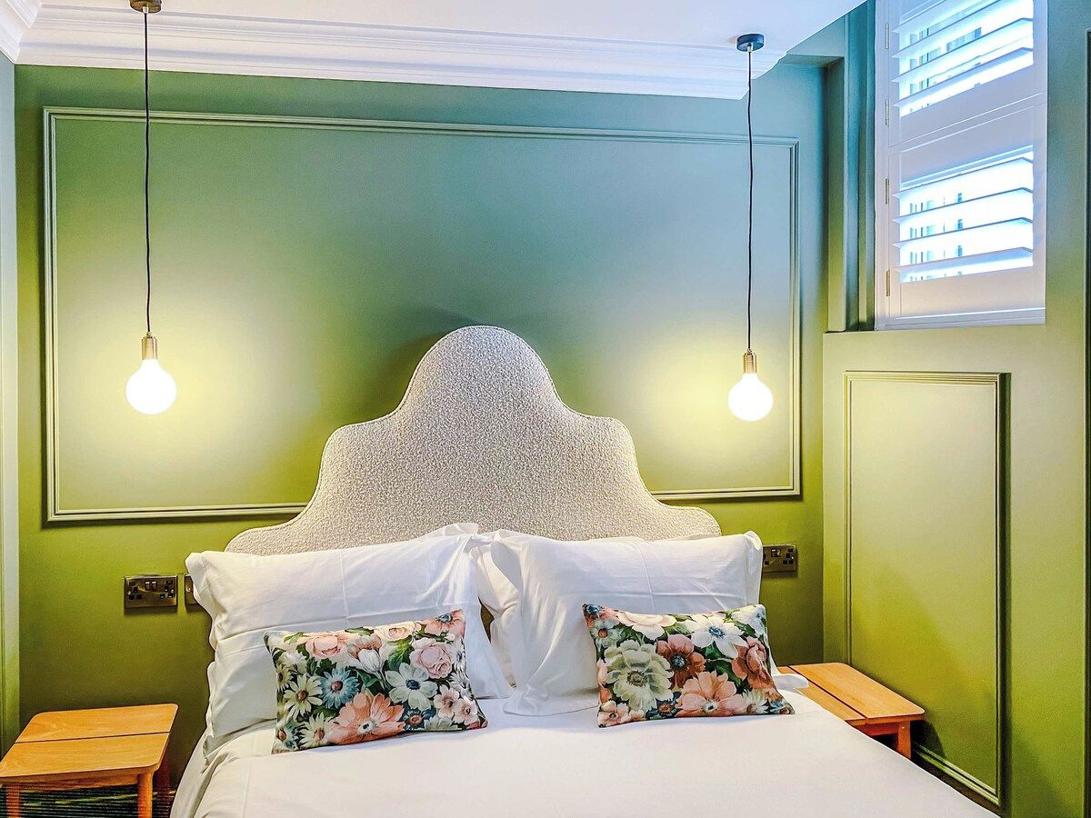 A bed with a textured headboard, two bedside lamps, and floral pillows.