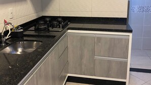 A kitchen with grey cabinets, a black countertop, a stainless steel sink, and a gas stove.
