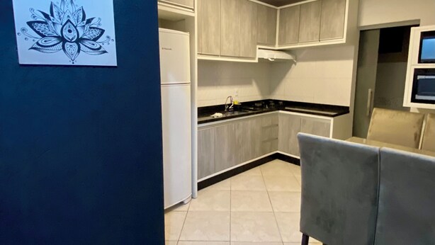 A modern kitchen with white cabinets, a black countertop, and a grey sofa.