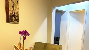 A dining area with a table, chairs, a vase with flowers, and a painting of the Eiffel Tower.