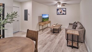 Una sala de estar moderna con una mesa de comedor de madera, un sofá, una mesa de centro y un televisor.