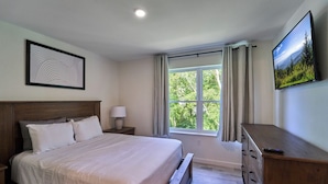 Un dormitorio con cama, mesita de noche, cómoda y ventana con cortinas.