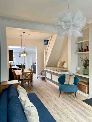 A modern living space with a dining area, a sofa, a chair, and a staircase.