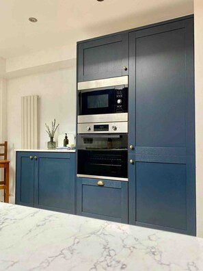 A kitchen with a built-in microwave, oven, and a cabinet with a handle.