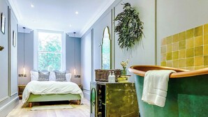 Quarto com cama, banheira verde e janela.