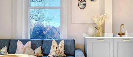 A living room with a sofa, a coffee table, and a window with a view of trees.