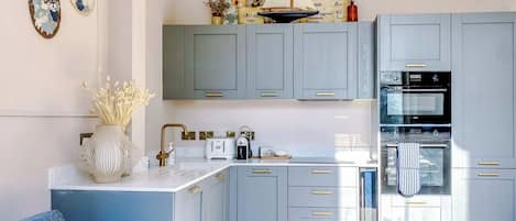 A modern kitchen with grey cabinets, a built-in oven, and a white countertop.