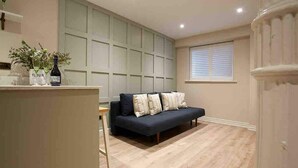 A modern living room with a dark sofa, a wooden floor, and a window with blinds. - Victoria Bar Walls - York Central & free park… (York)