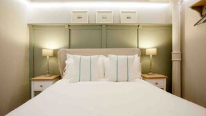 A hotel room with a large bed, two bedside tables with lamps, a headboard with storage compartments, and a column on the right. - Victoria Bar Walls - York Central & free park… (York)