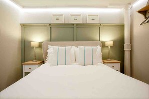 A hotel room with a large bed, two bedside tables with lamps, a headboard with storage compartments, and a column on the right. - Victoria Bar Walls - York Central & free park… (York)