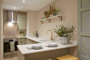 A modern kitchen with a central island, built-in oven, and a stainless steel range hood.