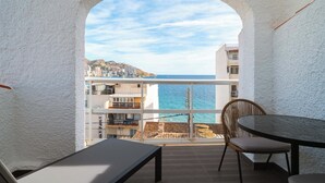 Un balcón con vista al mar, una mesa y una silla.