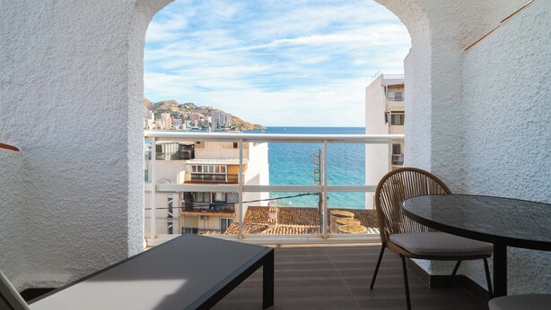Un balcón con vista al mar, una mesa y una silla.