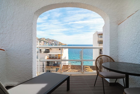 Un balcón con vista al mar, una mesa y una silla.