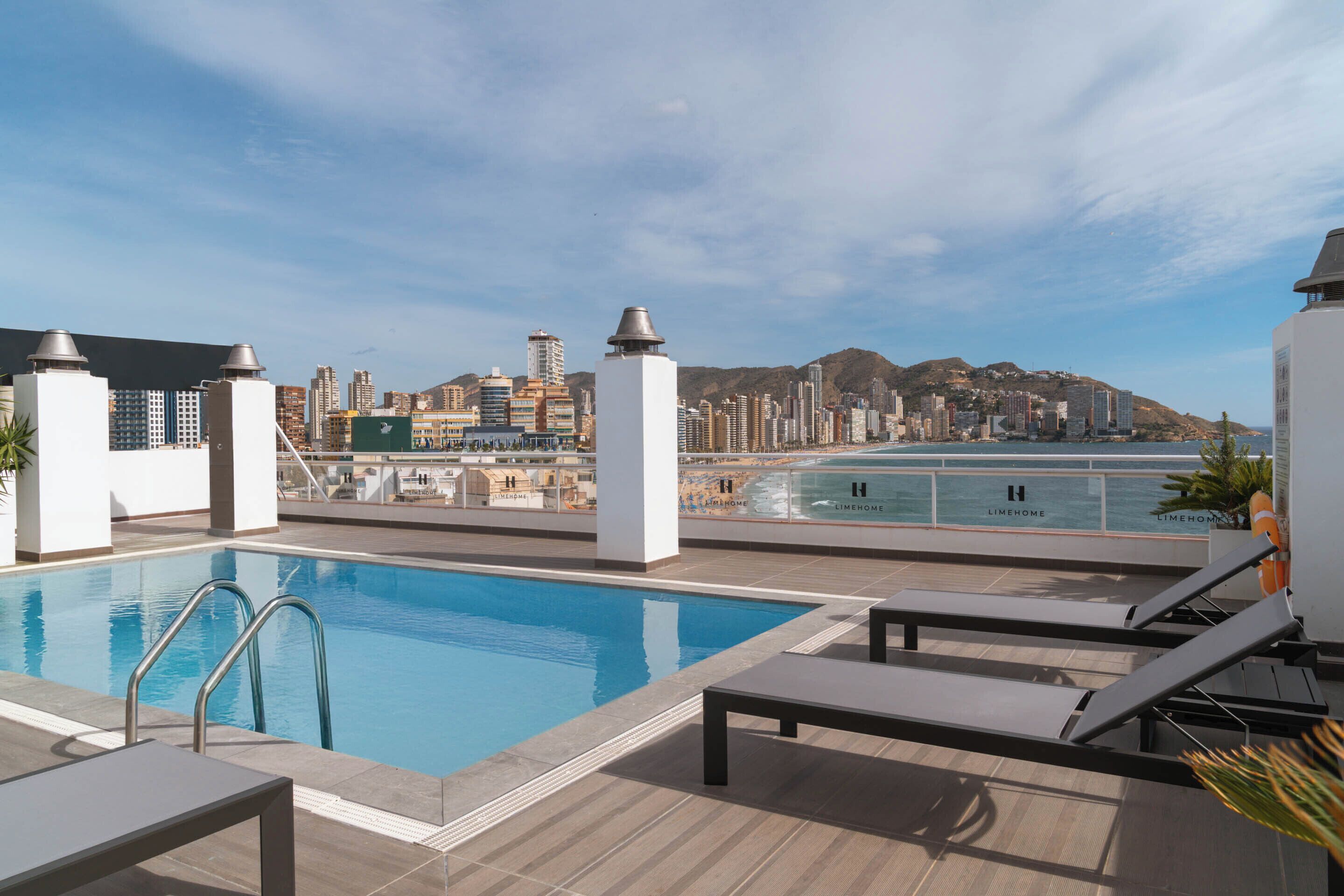A rooftop pool with a city view, lounge chairs, and a lifebuoy.