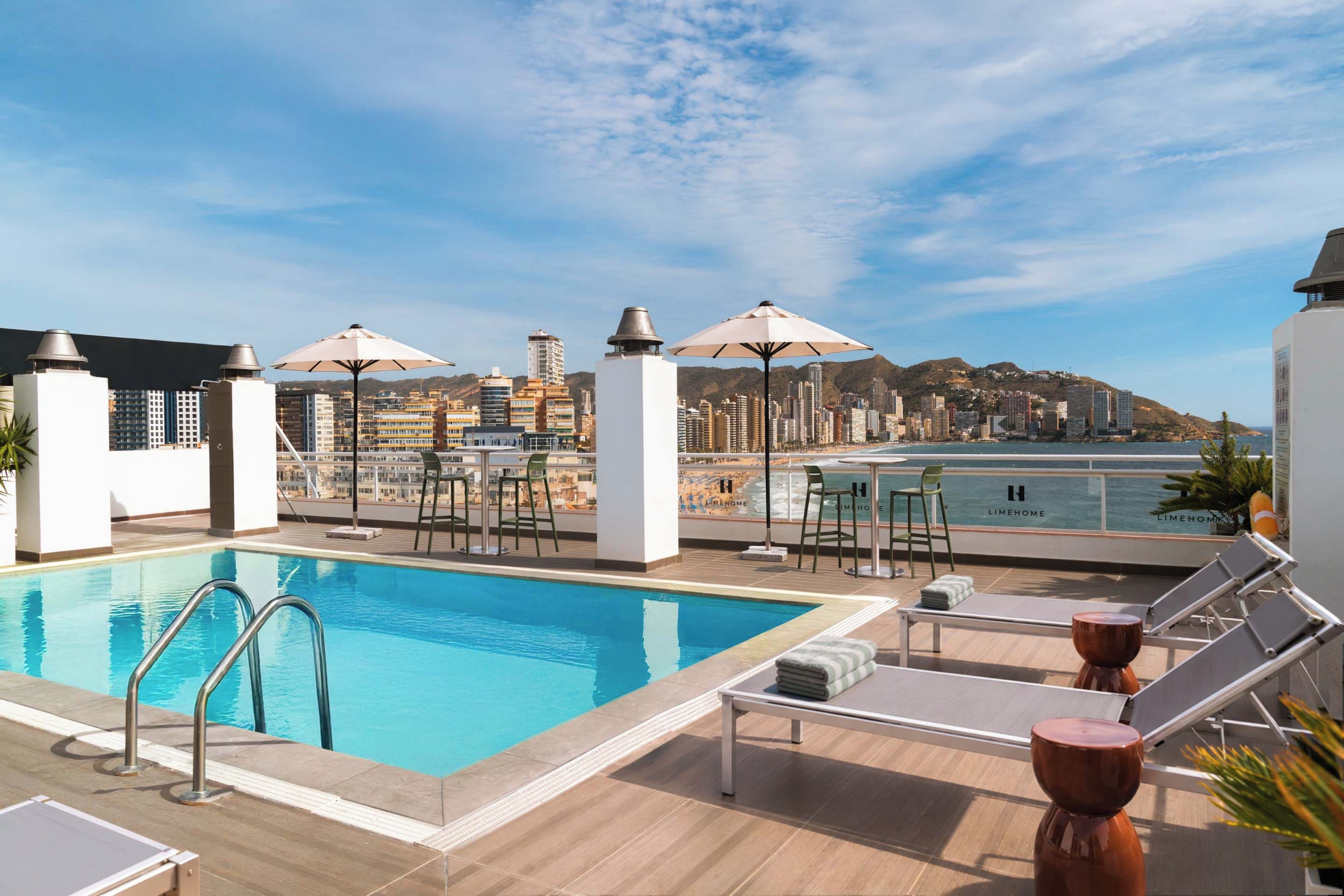 Área de piscina no terraço com vista para o horizonte urbano e a praia.