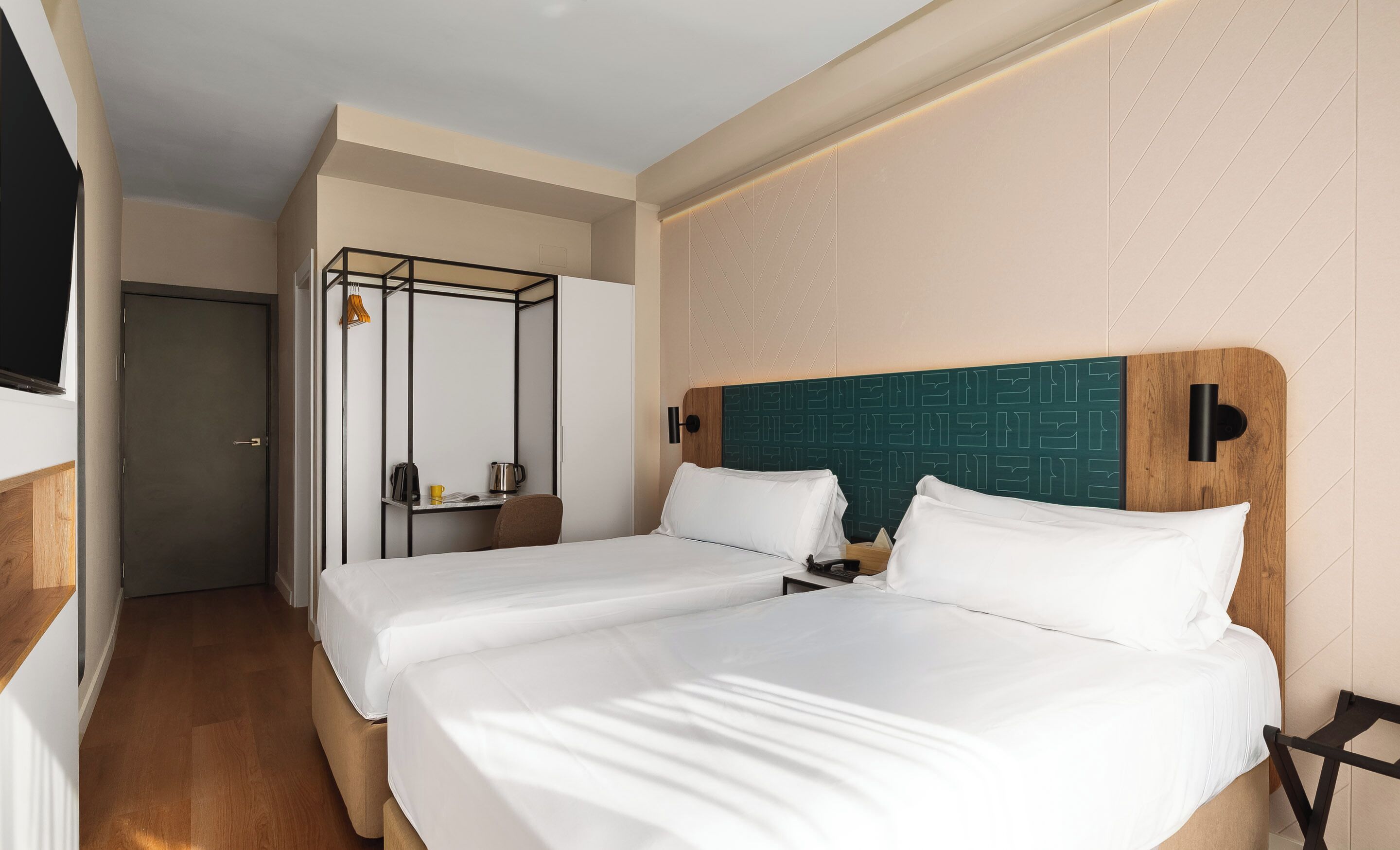 Une chambre d’hôtel avec deux lits, un bureau, une chaise et une armoire.