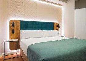 Une chambre moderne avec un lit, une table de chevet et un luminaire fixé au mur.