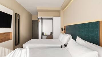 A hotel room with a bed, a desk, a chair, a television, and a wall-mounted mirror.