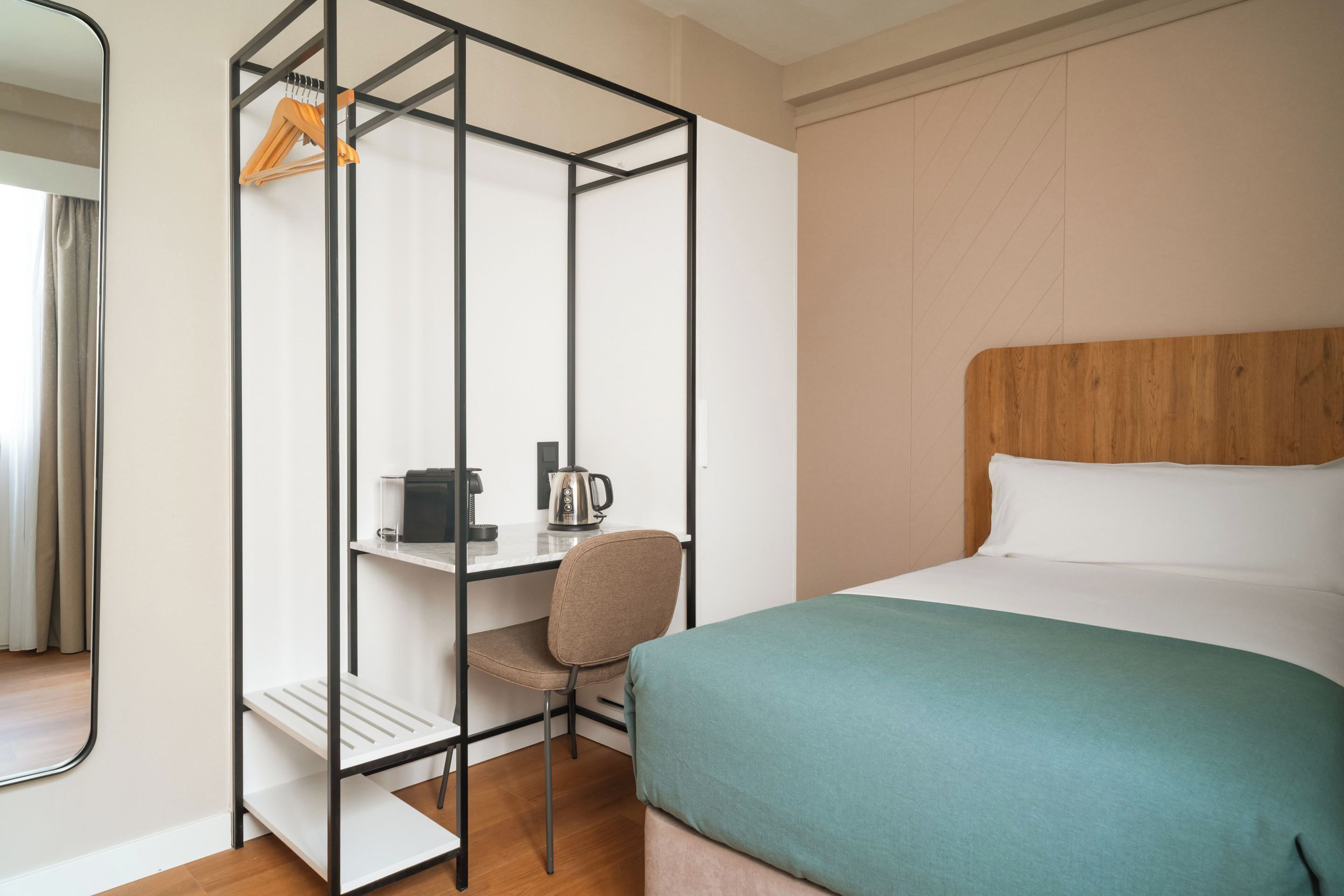 A hotel room with a bed, a desk, and a chair.