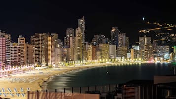 A nighttime cityscape with a beach and high-rise buildings.