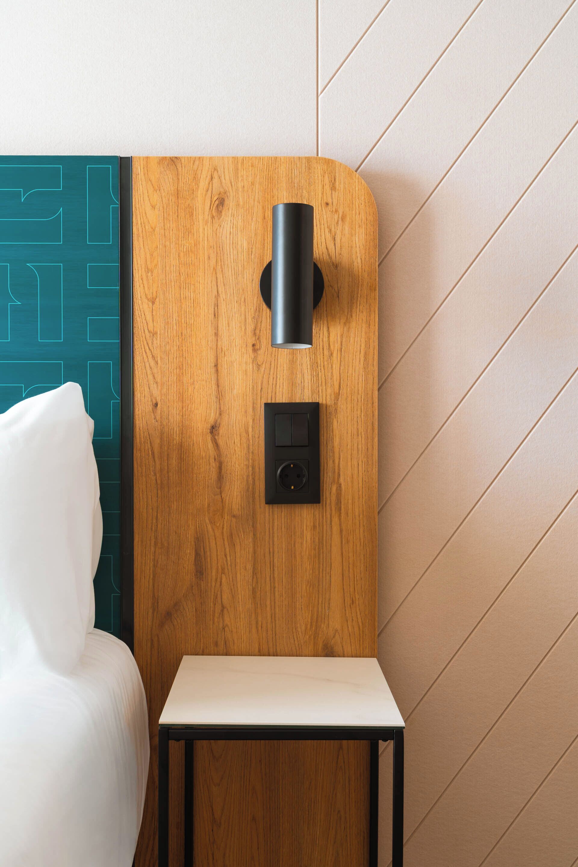 Une chambre moderne avec un mur d’accent en bois, une petite table et un luminaire fixé au mur.