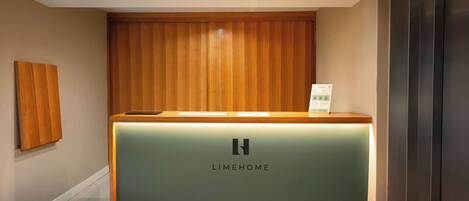 A reception desk with a wooden panel and a green counter, featuring the logo 'LIMEHOME'.