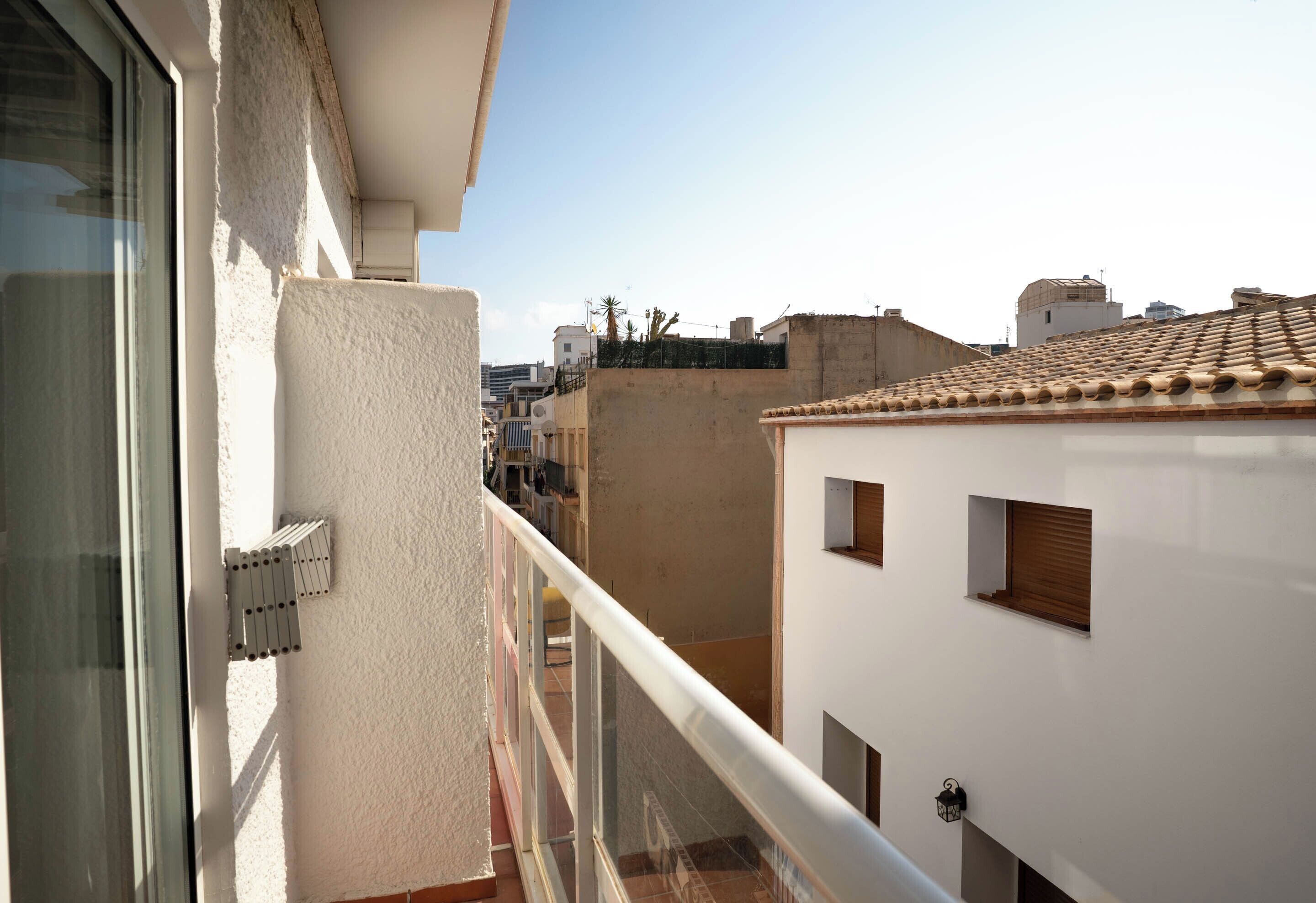 A balcony with a view of adjacent buildings and a clear sky.