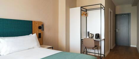 Une chambre d’hôtel comprenant un lit, un bureau avec une chaise, une armoire et une porte.