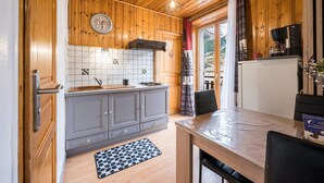 Une cuisine avec des meubles de rangement en bois, un pare-feu en carrelage, une horloge et une machine à café.