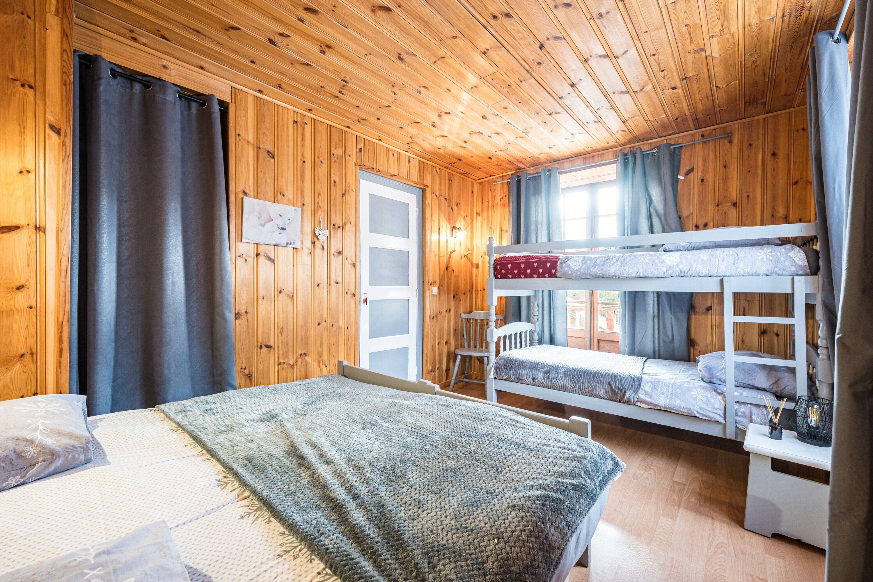 Une pièce de cabane en bois avec des lits superposés, un lit simple, une chaise et une petite table.
