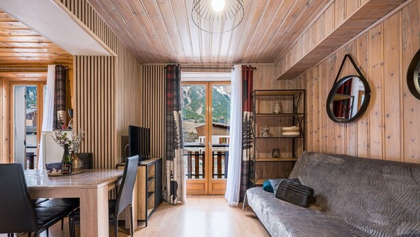 Un intérieur en bois comprenant un canapé, une table à manger, des chaises et un téléviseur.