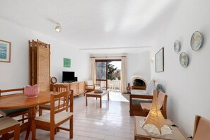 A spacious living area with a dining table, chairs, a sofa, a television, and a fireplace.