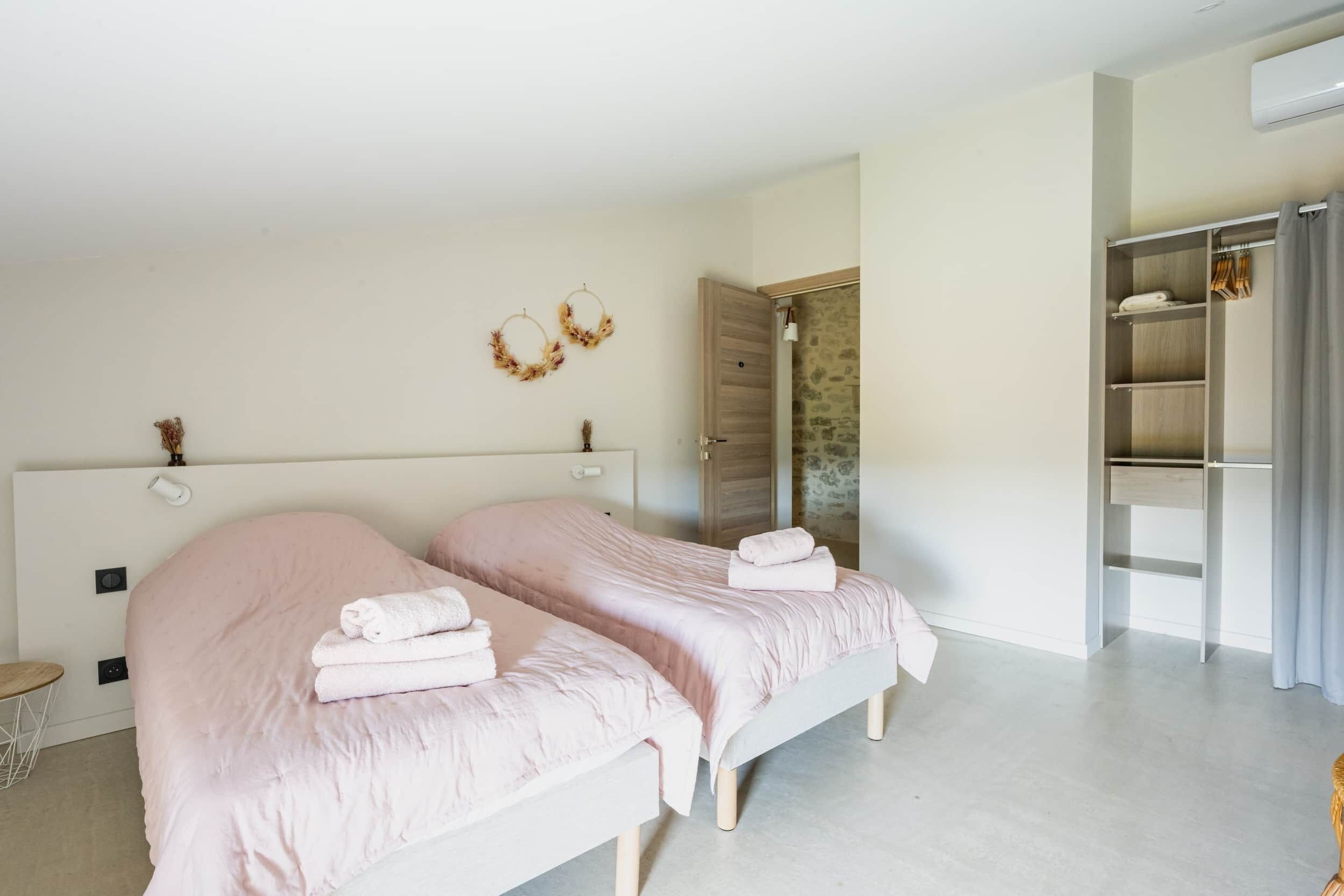 A bedroom with two beds, a wardrobe, and a bathroom door.
