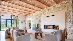 Un salon spacieux avec un mur en pierre, une cheminée et une grande fenêtre donnant sur l’extérieur.