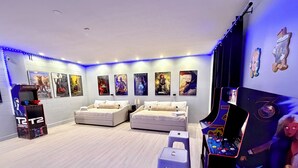 Une chambre avec deux lits, une console de jeux et des affiches de films accrochées au mur.