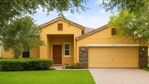 Une maison à deux étages avec une façade jaune, une porte d’entrée marron et un garage.