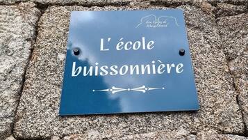 A sign on a stone surface with the text 'L'école buissonnière' and a logo.
