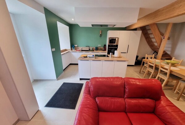 A modern kitchen with white cabinets, a black oven, and a dining area with wooden chairs and a table.