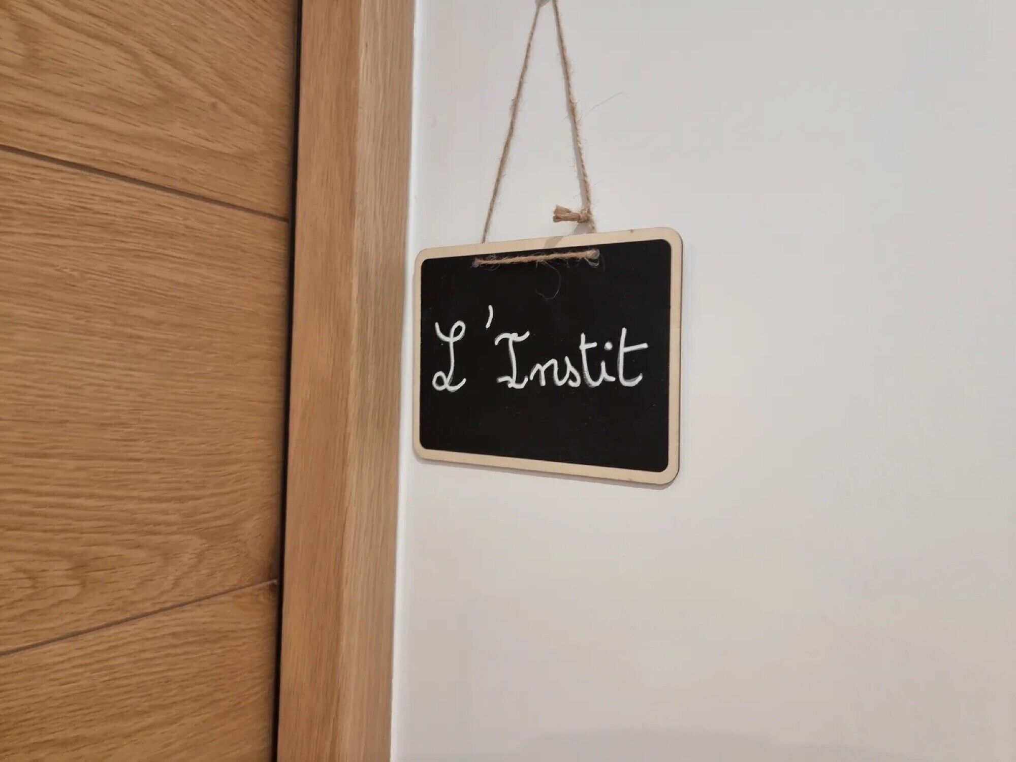 A blackboard with 'L'Institut' written on it, hanging on a wall.