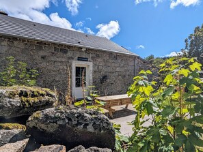 A stone building with a tiled roof, a wooden bench, and a sign reading 'L'école brissommière'.