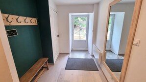 A hallway with a bench, a door, a mirror, and a sign on the wall. - Cottage “L'École Buissonnière de Mazalibrand”: Mountain View, Private Terrace & Garden (Mazet-Saint-Voy)