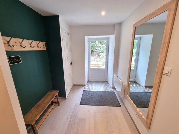 A hallway with a bench, a door, a mirror, and a sign on the wall.