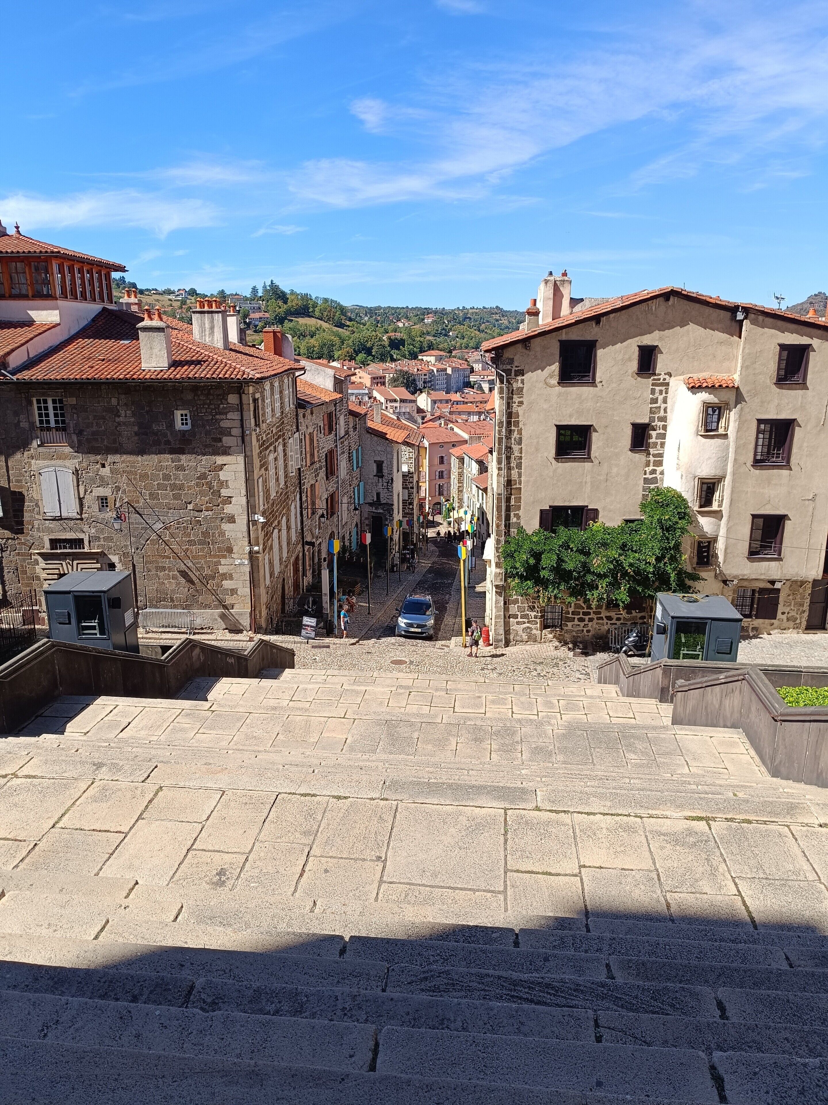 A stone staircase leading down to a street with buildings on either side.