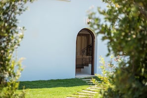 A pathway leading to an arched entrance with a staircase and a railing.