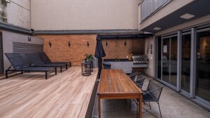 An outdoor patio with a wooden table and chairs, a grill, and a brick wall. - 4 Minutes From Arcos da Lapa M404b (Rio de Janeiro)