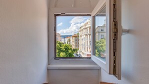 A narrow corridor with a window leading to a balcony overlooking a cityscape with buildings and trees. - ATTIC URBAN AP4485 by Riviera Holiday Homes (Niza)