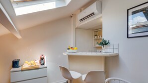 A compact kitchen with a dining area, a white countertop with a fruit bowl, a toaster, and a coffee maker. - ATTIC URBAN AP4485 by Riviera Holiday Homes (Niza)