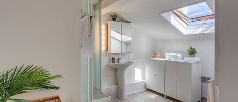 A modern bathroom with a skylight, a large mirror, and a white sink.